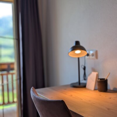 Scrivania nell'agriturismo con lampada e sedia, con accesso al balcone e vista sulle montagne.