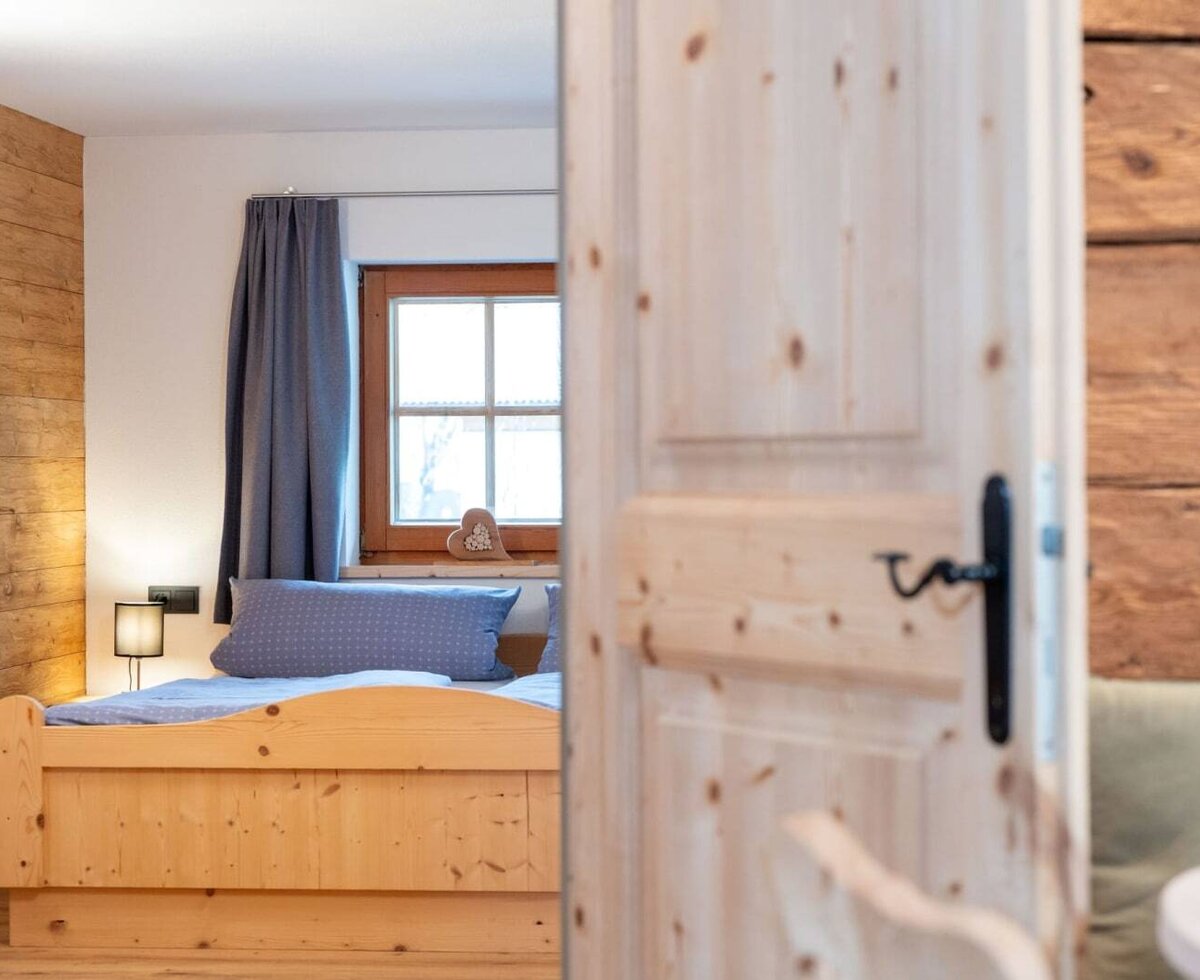 Camera da letto nell'appartamento con letto in legno, finestra e parete in legno.