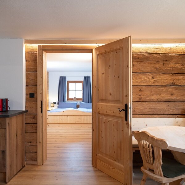 Zona cucina e pranzo dell'Ap­par­te­ments, con arredi in legno e accesso a una camera da letto.