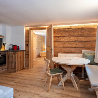 Cucina e zona pranzo dell'Ap­par­te­ments con elettrodomestici moderni, forno e tavolo in legno con panca ad angolo.