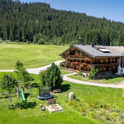 L'idilliaco agriturismo degli appartamenti, caratterizzato da un ampio giardino verde con parco giochi per bambini, sullo sfondo di un fitto bosco.