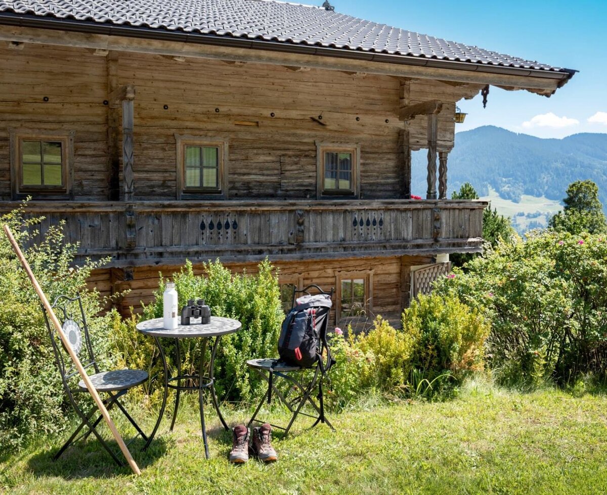 L'esterno idilliaco del agriturismo con un'accogliente area salotto in giardino e una vista panoramica sulle montagne.