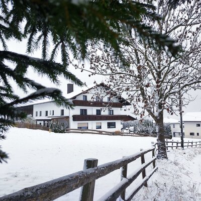 Vista esterna dell'agriturismo in inverno, con un paesaggio innevato e una recinzione in legno.