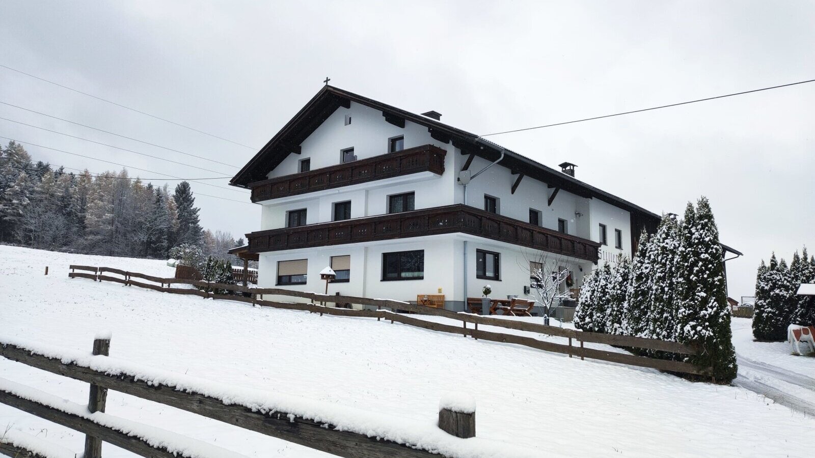 Vista esterna dell'agriturismo in inverno, circondato dalla neve e da una recinzione in legno.