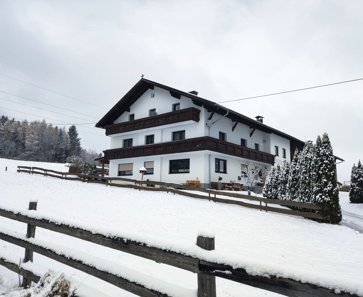 Vista esterna dell'agriturismo in inverno, circondato dalla neve e da una recinzione in legno.