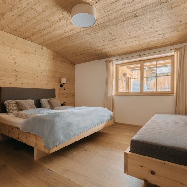 Camera da letto della Ferienwohnung con letto matrimoniale, divano letto e rivestimenti in legno.