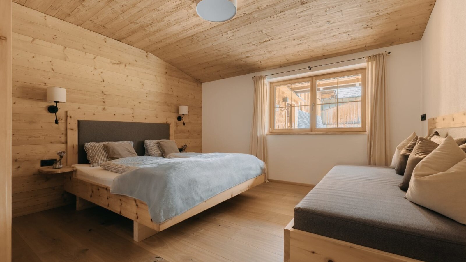 Camera da letto della Ferienwohnung con letto matrimoniale, divano letto e rivestimenti in legno.