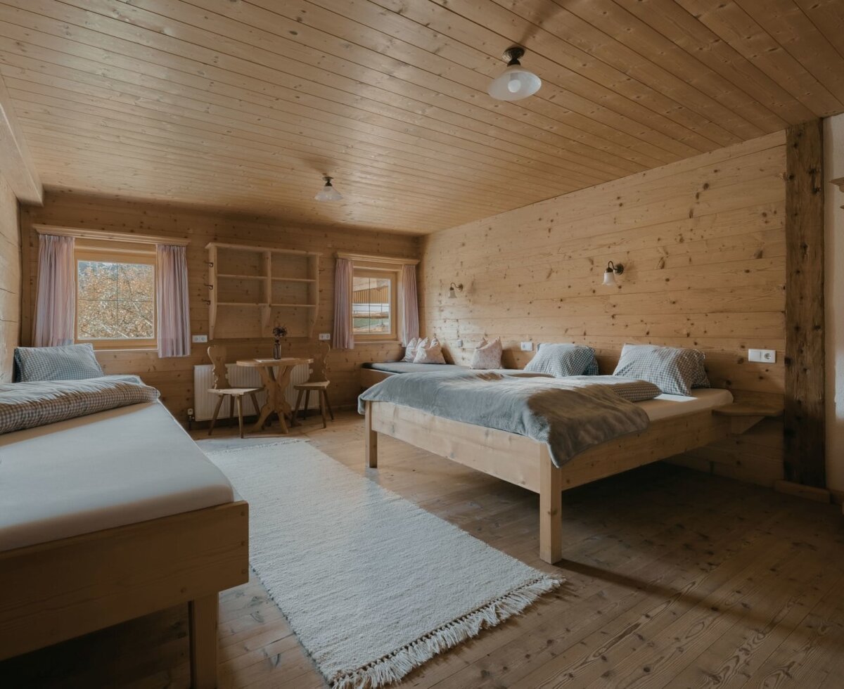 Camera da letto della Ferienwohnung con letto matrimoniale, letto singolo, pareti in legno e una piccola zona pranzo.