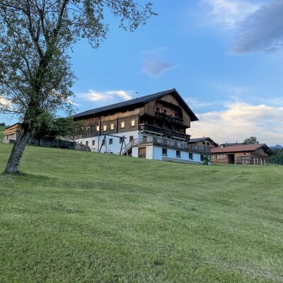 La Ferienwohnung è un edificio tradizionale in legno con balconi, situato su una collina verde.