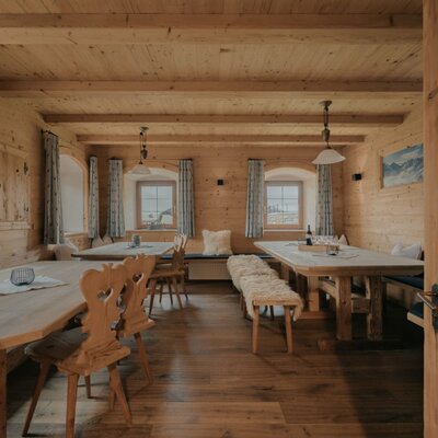 Zona pranzo della Ferienwohnung con tavoli, panche e sedie in legno per pasti conviviali.