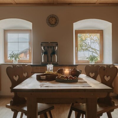 Cucina e zona pranzo completamente attrezzate nell'appartamento vacanze, con tavolo in legno, sedie e vista sul paesaggio.