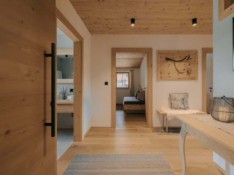 L'ingresso della Ferienwohnung, con pavimento e soffitto in legno, una panca e accesso alle altre stanze.