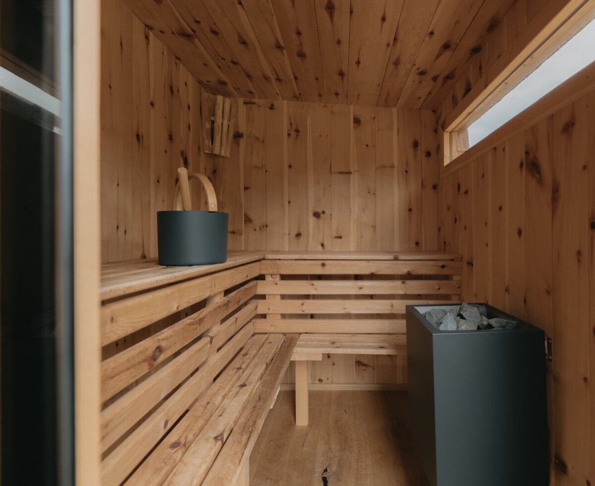 La sauna privata nell'appartamento vacanze, dotata di panche in legno, stufa per sauna e accessori.
