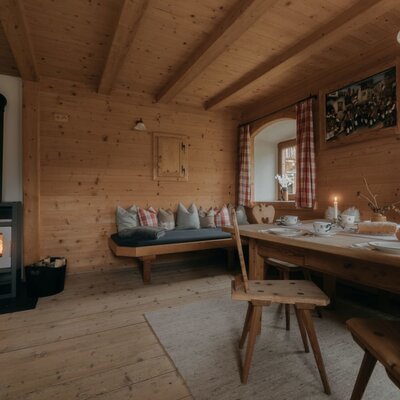 Zona pranzo della Ferienwohnung con tavolo in legno, panca e stufa a legna.