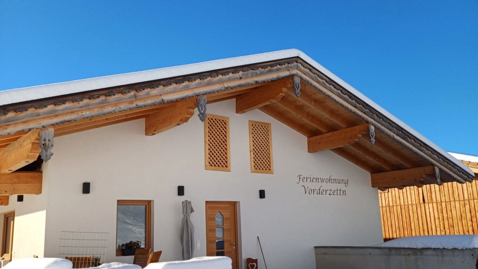L'esterno invernale dell'agriturismo 'Ferienwohnung Vorderzettla', coperto di neve sotto un cielo azzurro.