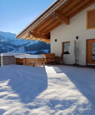 La terrazza innevata del Bauernhof, con mobili da esterno e vista sul paesaggio montano invernale.