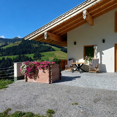 La soleggiata terrazza dell'agriturismo con comode sedute, fioriere colorate e una splendida vista sulle montagne.
