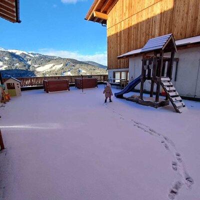 L'area esterna innevata del Bauernhof, con parco giochi per bambini e vista sulle montagne.