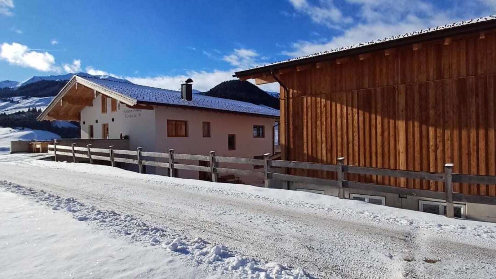 Il maso in inverno, con una strada di accesso innevata e un annesso in legno.