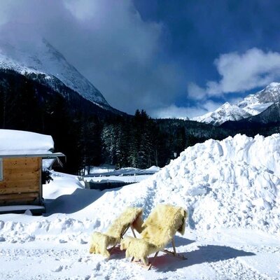 Invitanti sedie a sdraio con calde coperte di pelliccia nella neve all'esterno degli appartamenti, circondate da un suggestivo panorama montano innevato.