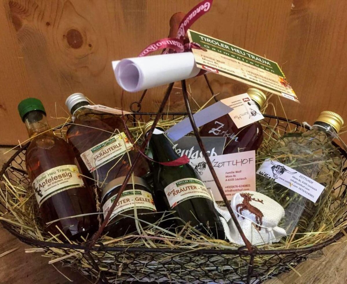Un cesto regalo preparato con cura dall'appartamento, ricco di specialità tipiche tirolesi adagiate sul fieno.