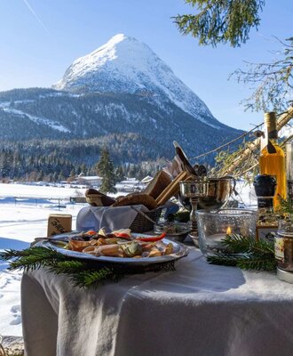 Un invitante tavolo all'aperto dell'appartamento con deliziosi spuntini e una suggestiva vista sulle montagne innevate.