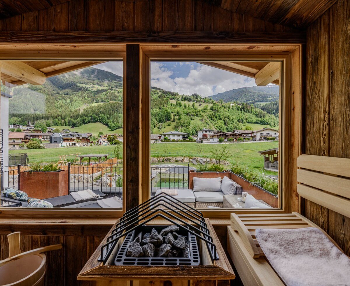 Sauna nell'agriturismo con interni in legno, stufa per sauna e vista sulle montagne e sul paese.